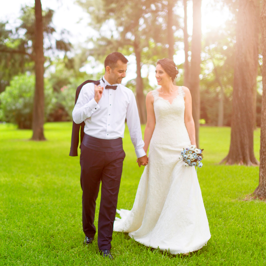 couple in wedding attire walking through orchard