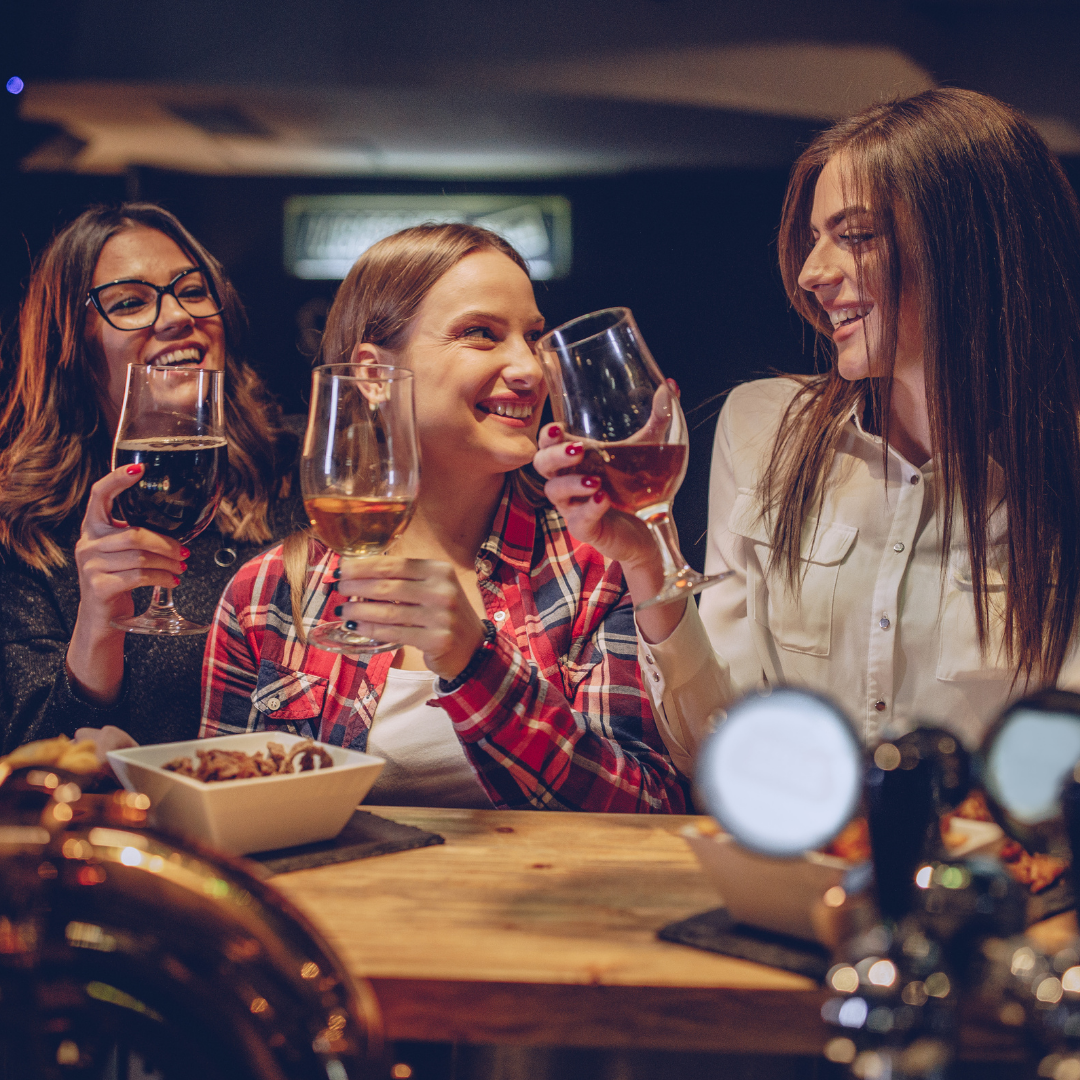 3 young women in a bar with wineglasses