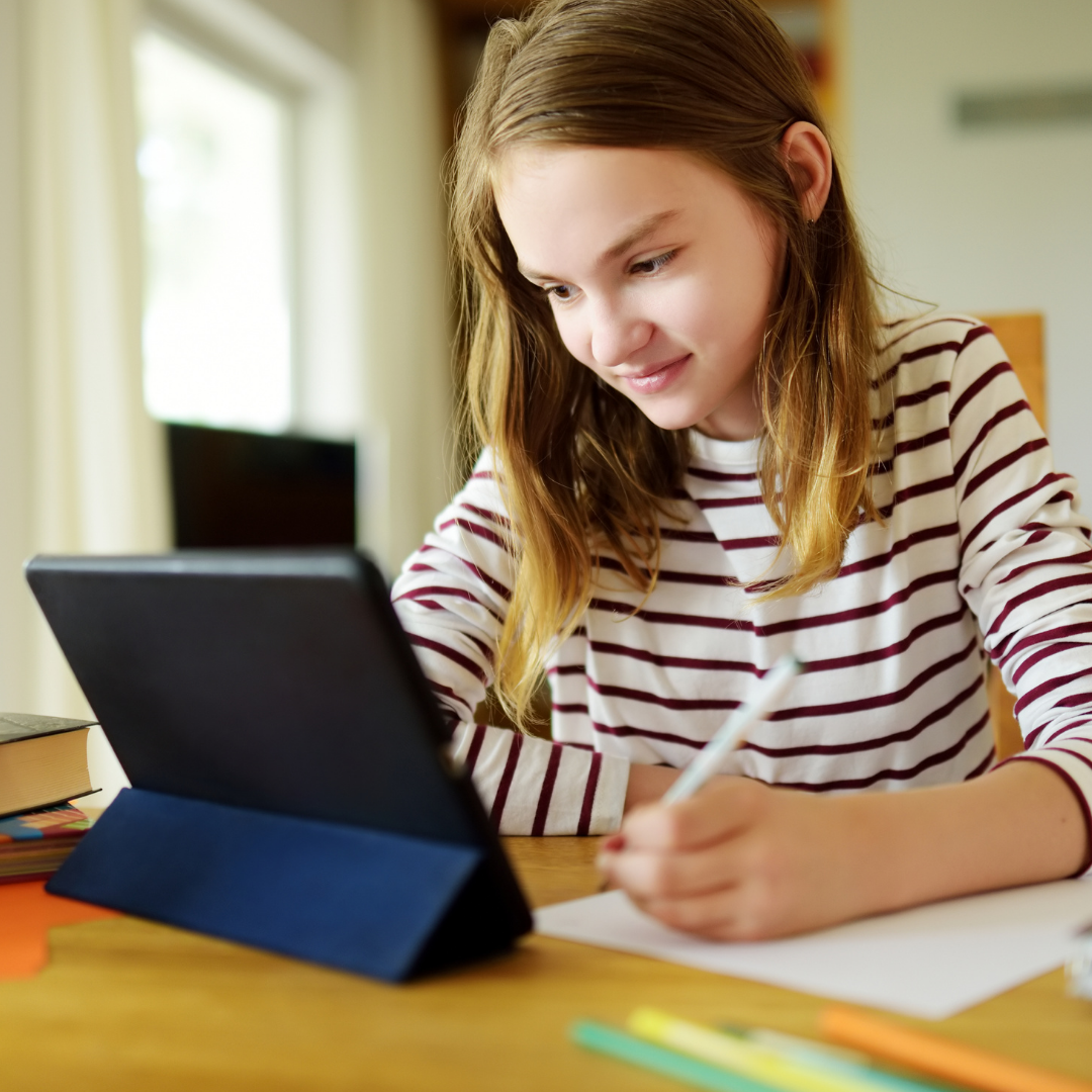preteen girl studying with notebook and tablet