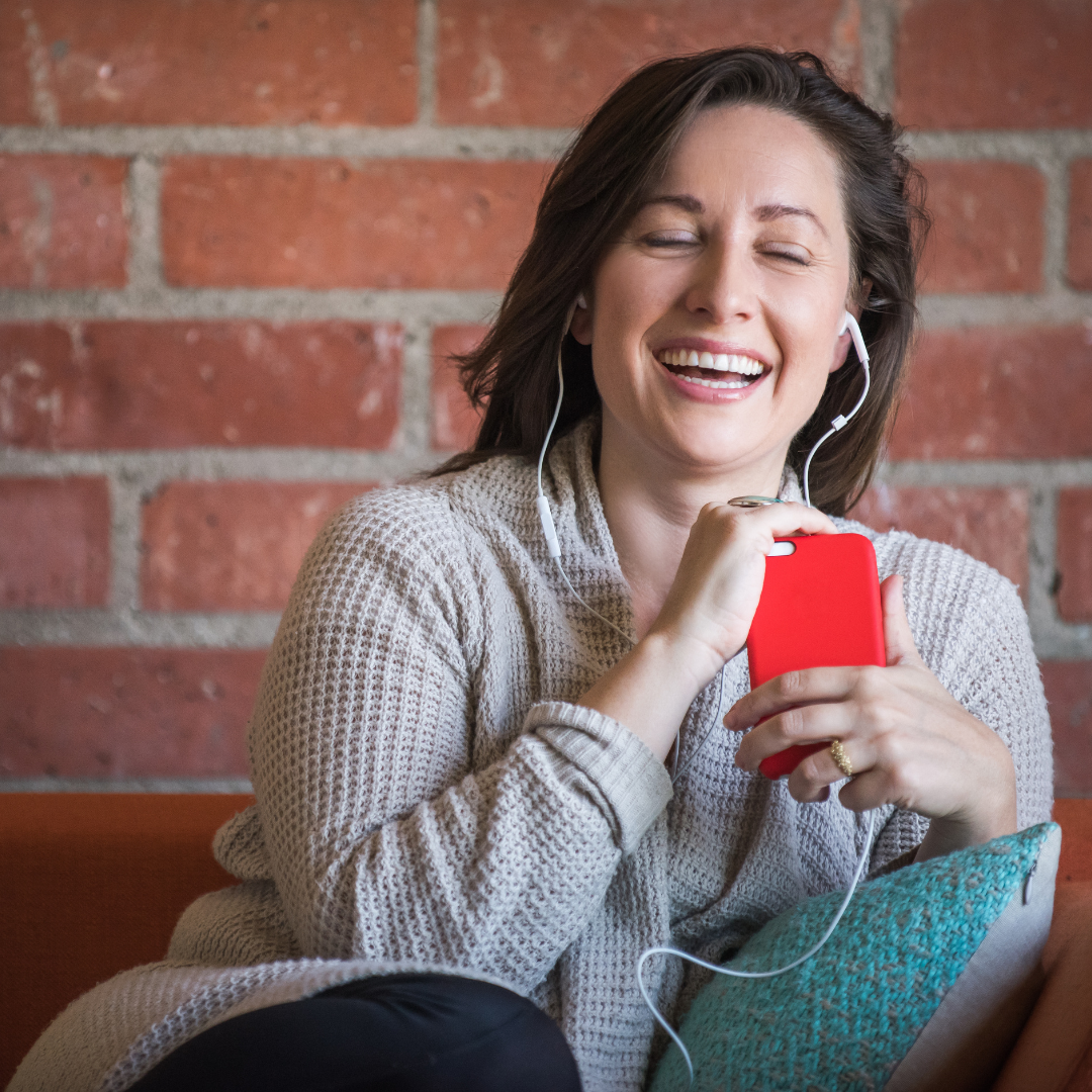 woman smiling and listening to podcast