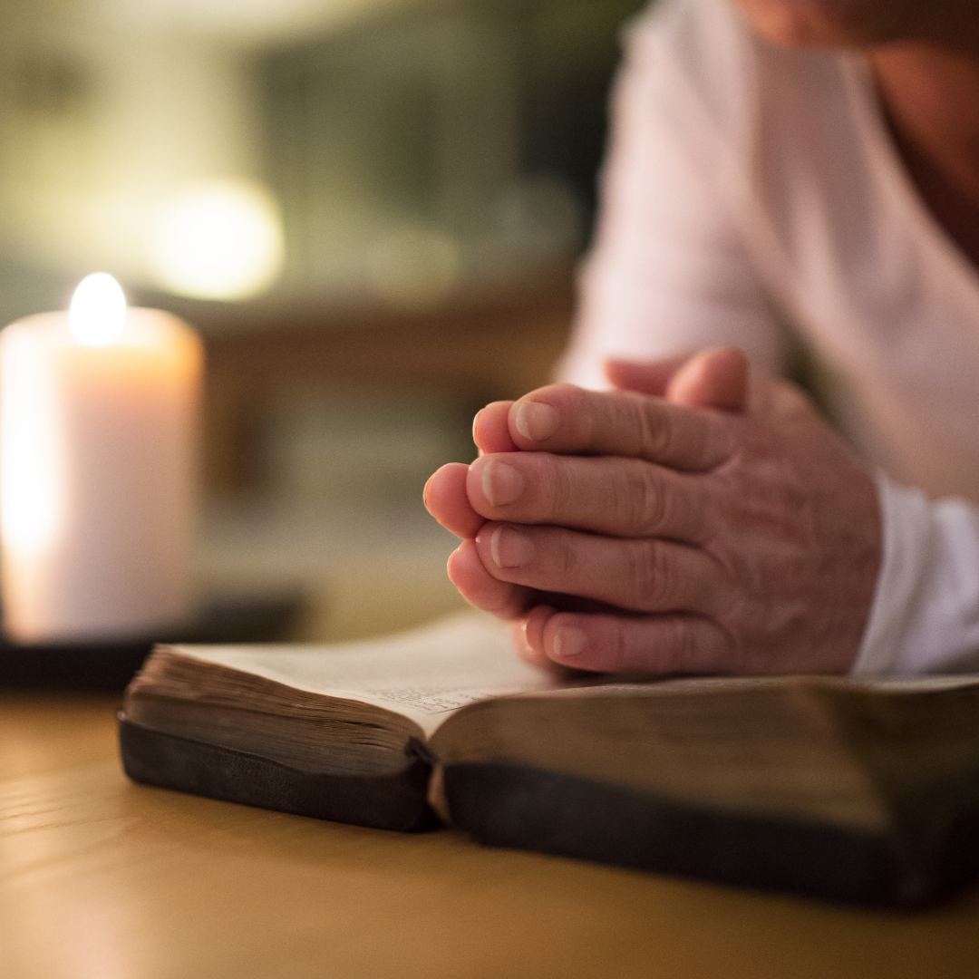 woman praying with Bible and candles