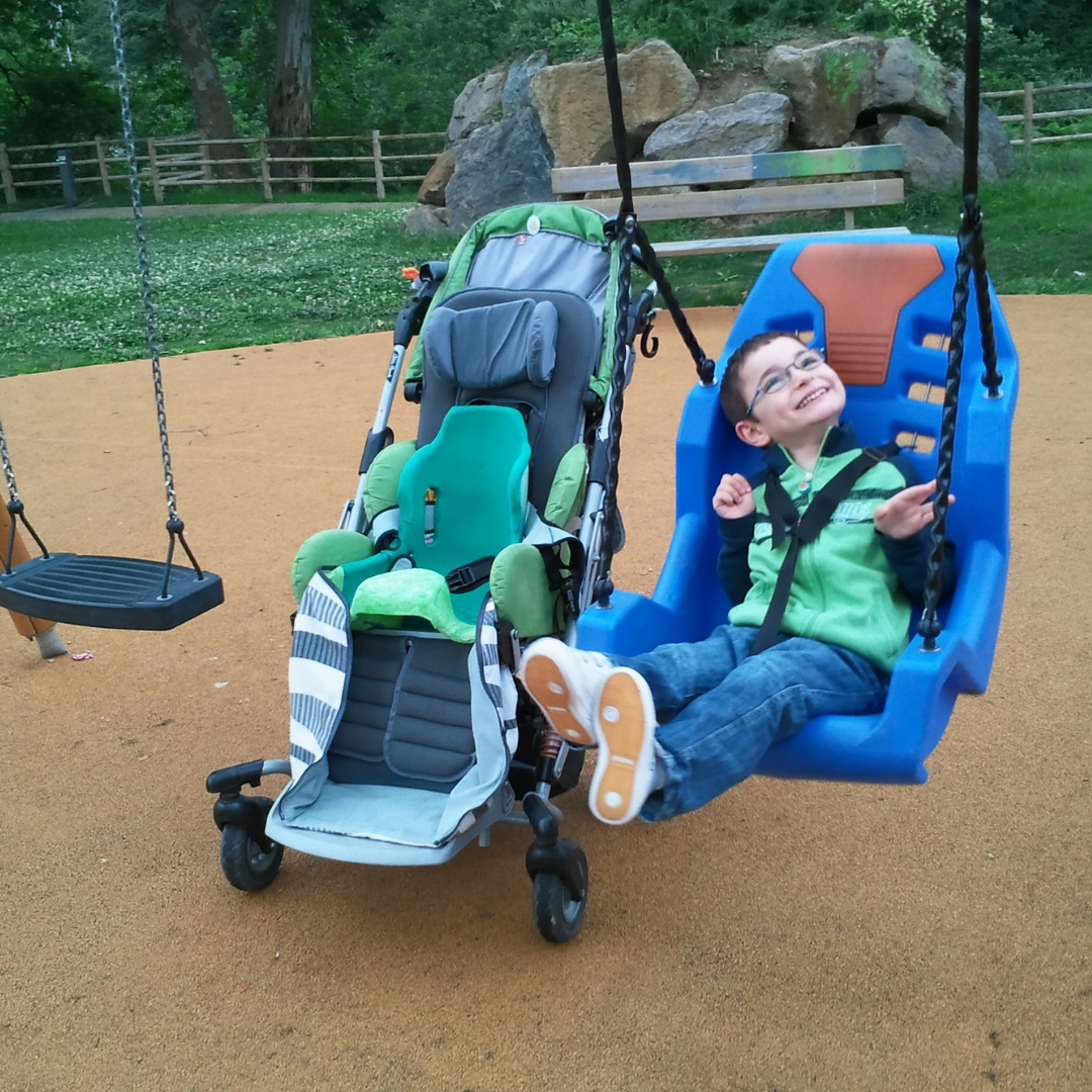 child using accessible swing, next to wheelchair