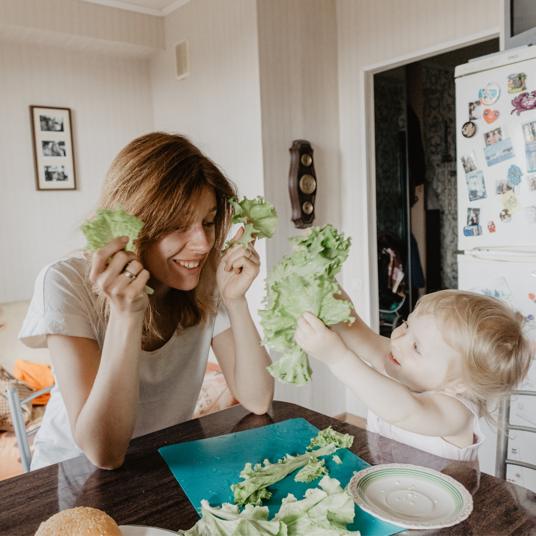 Mom and toddler playing with lettuce leaves