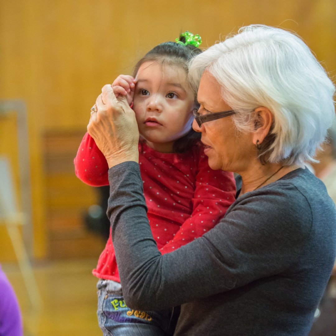 woman teaching small child to make sign of the cross