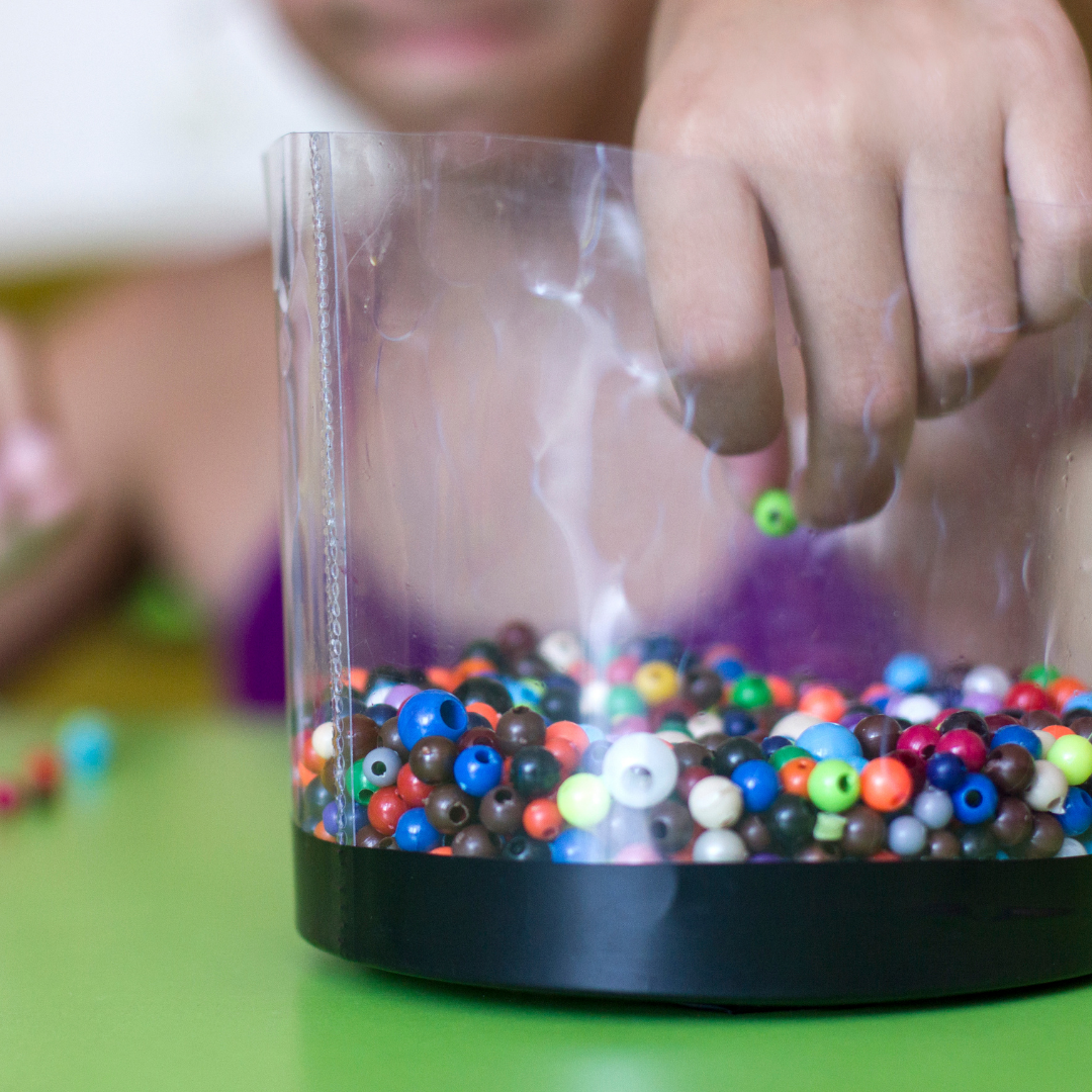 child reaching into a tub of beads