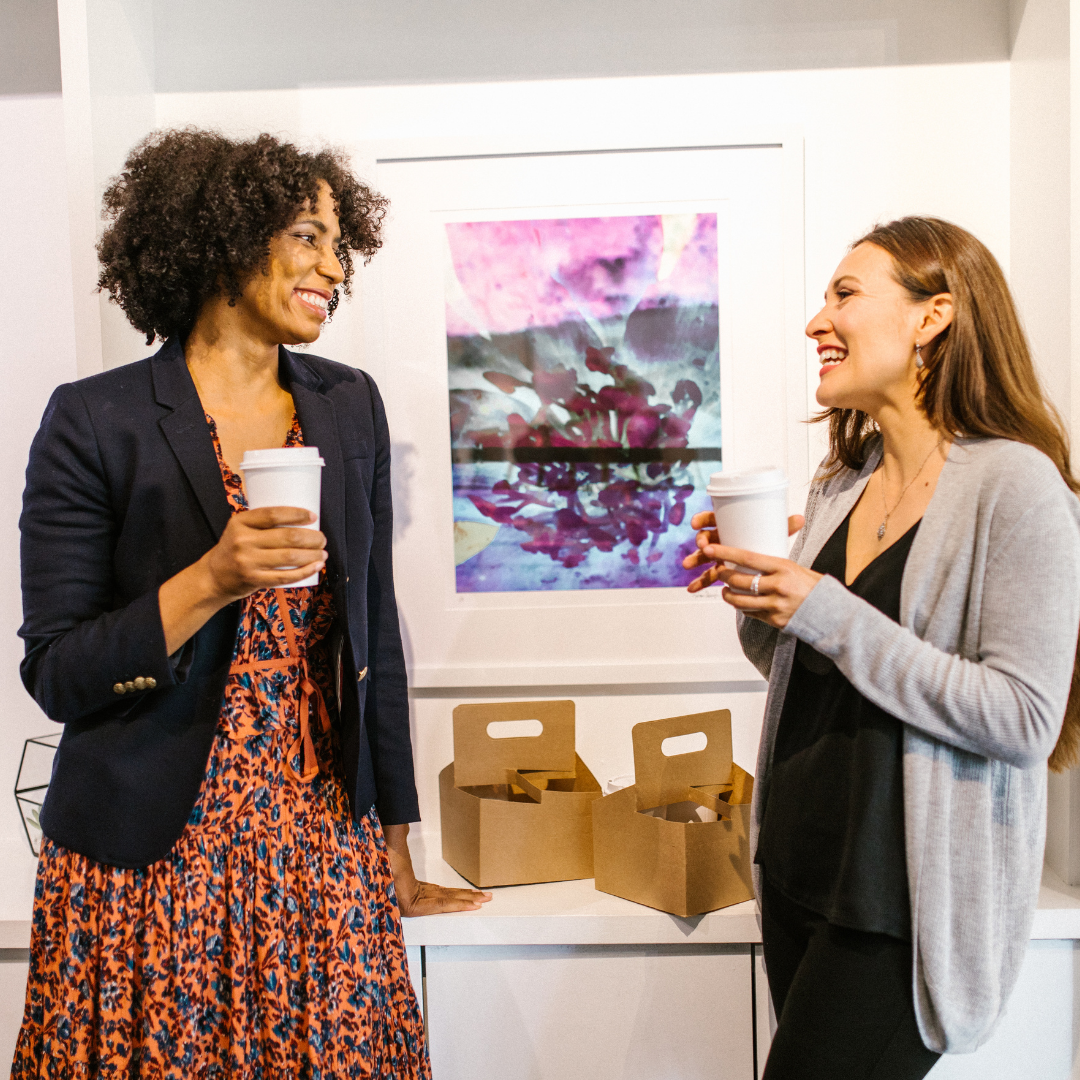2 women having a conversation, holding cups of coffee