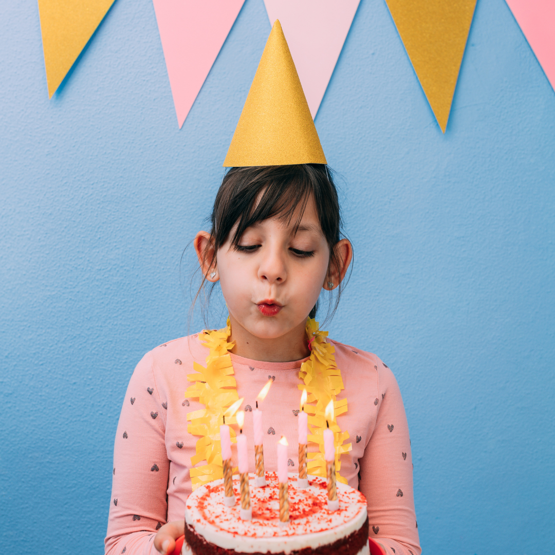 girl blowing out birthday candles on a cake