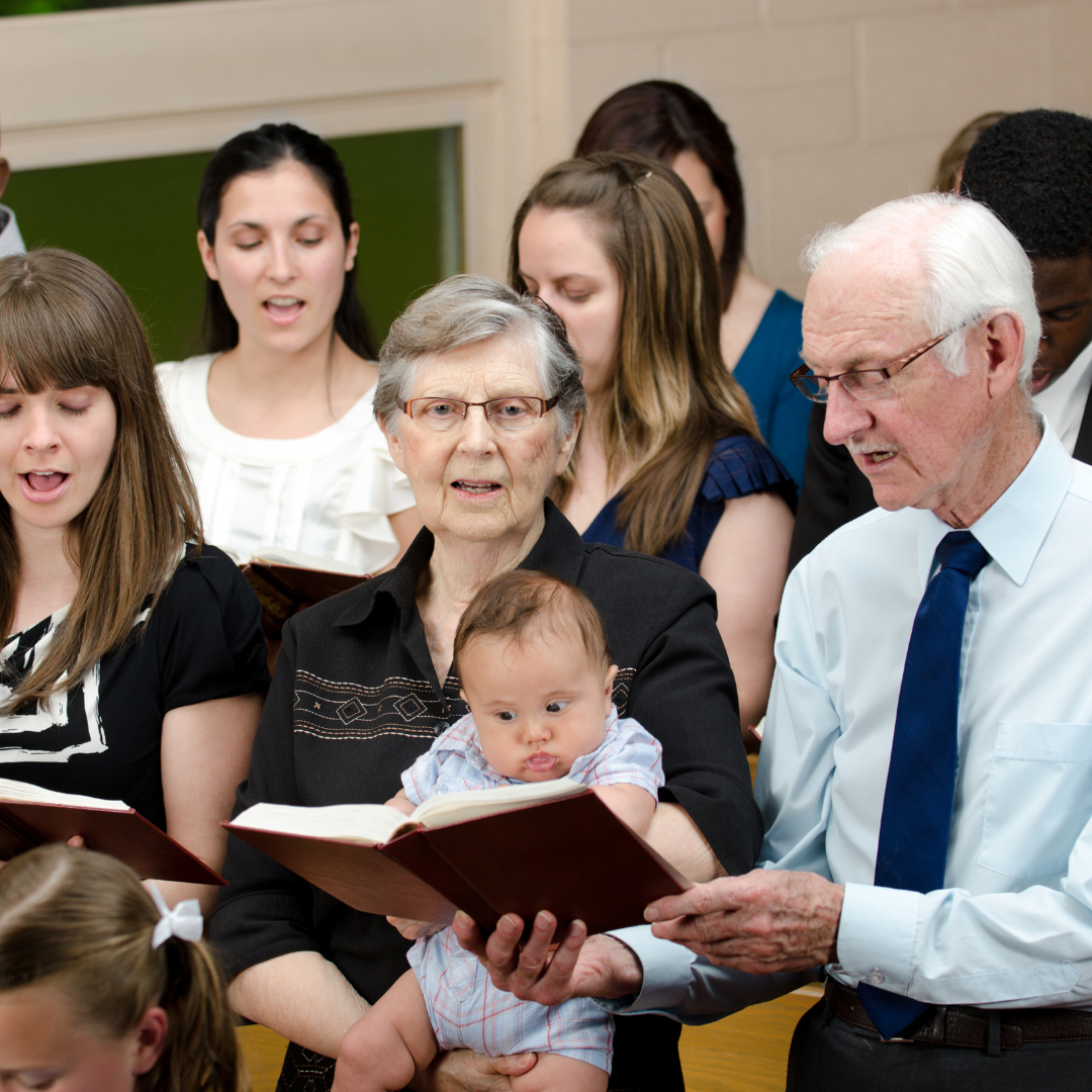 grandmother holding baby in church, singing from a hymnal