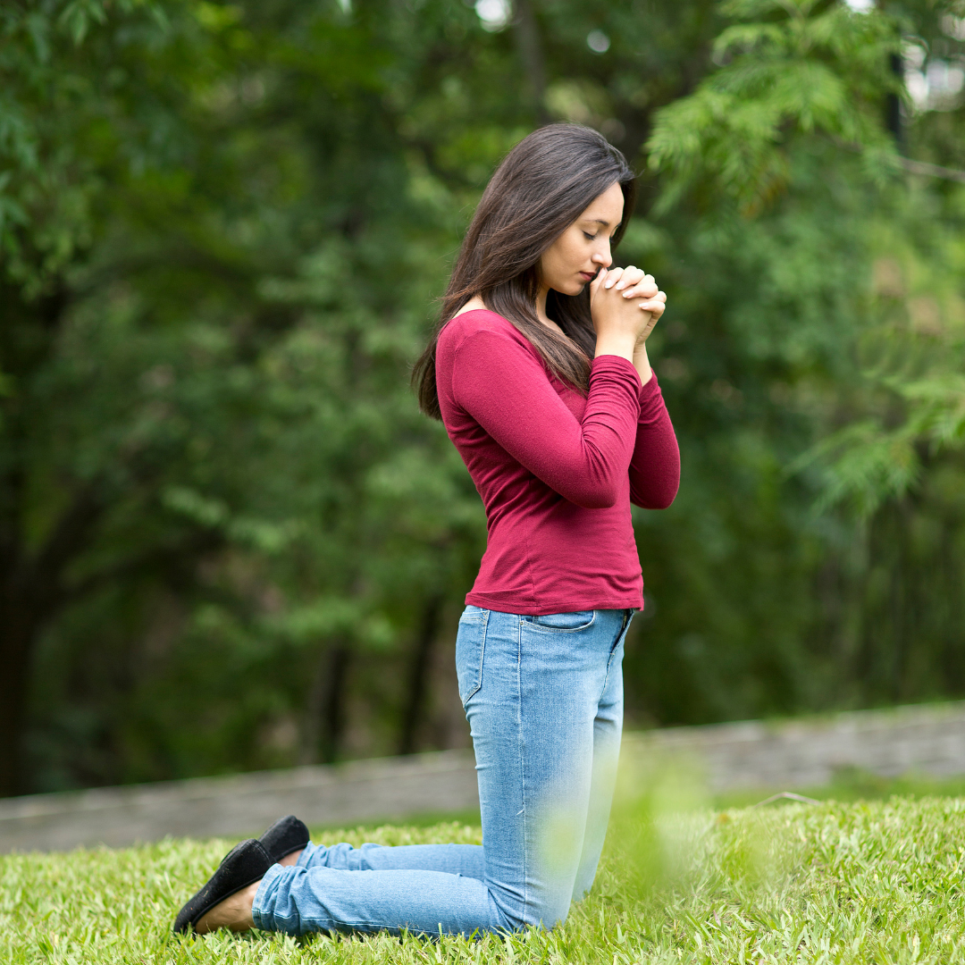 woman kneeling outside praying
