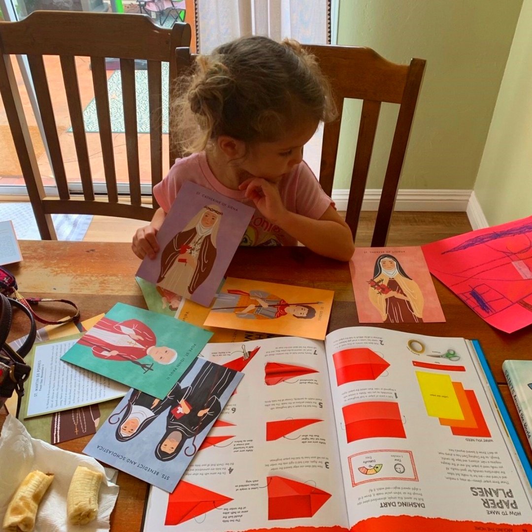 child playing with saint holy cards