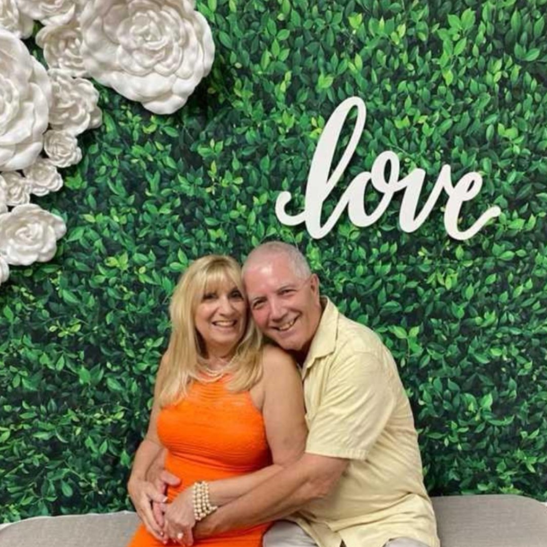 married couple in front of a sign reading "love"