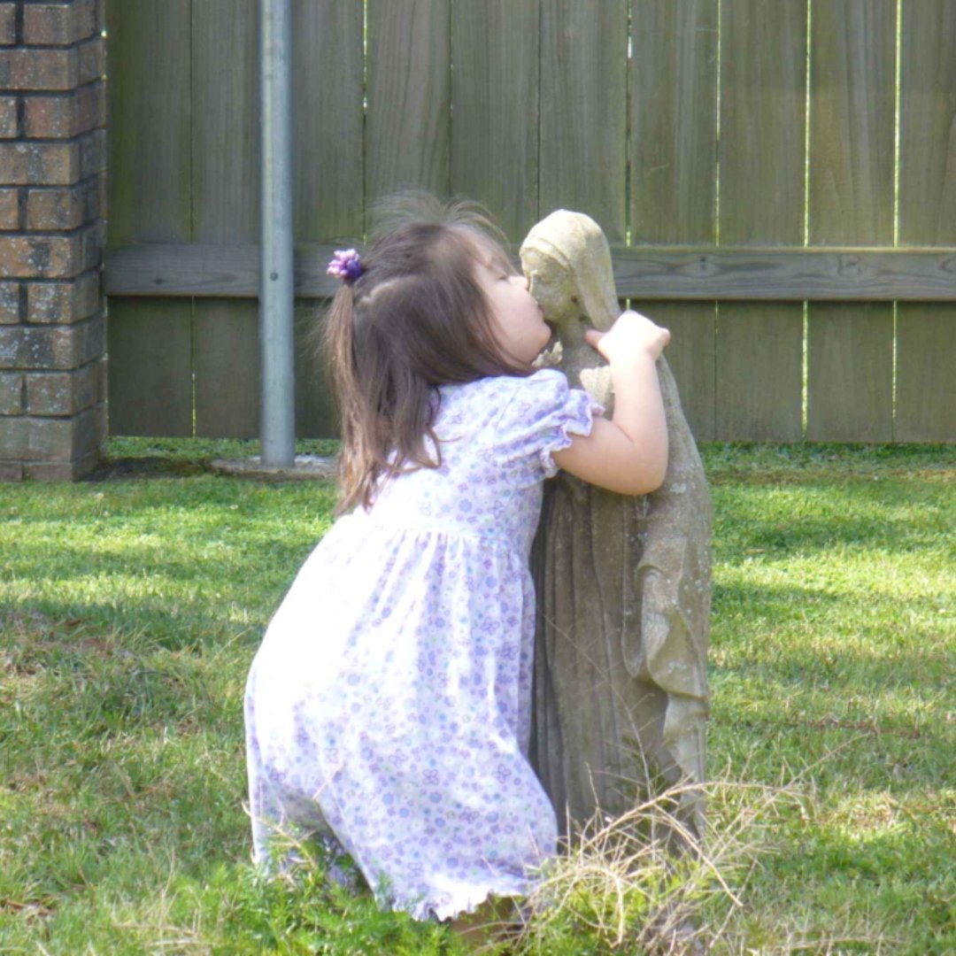little girl kissing Mary statue