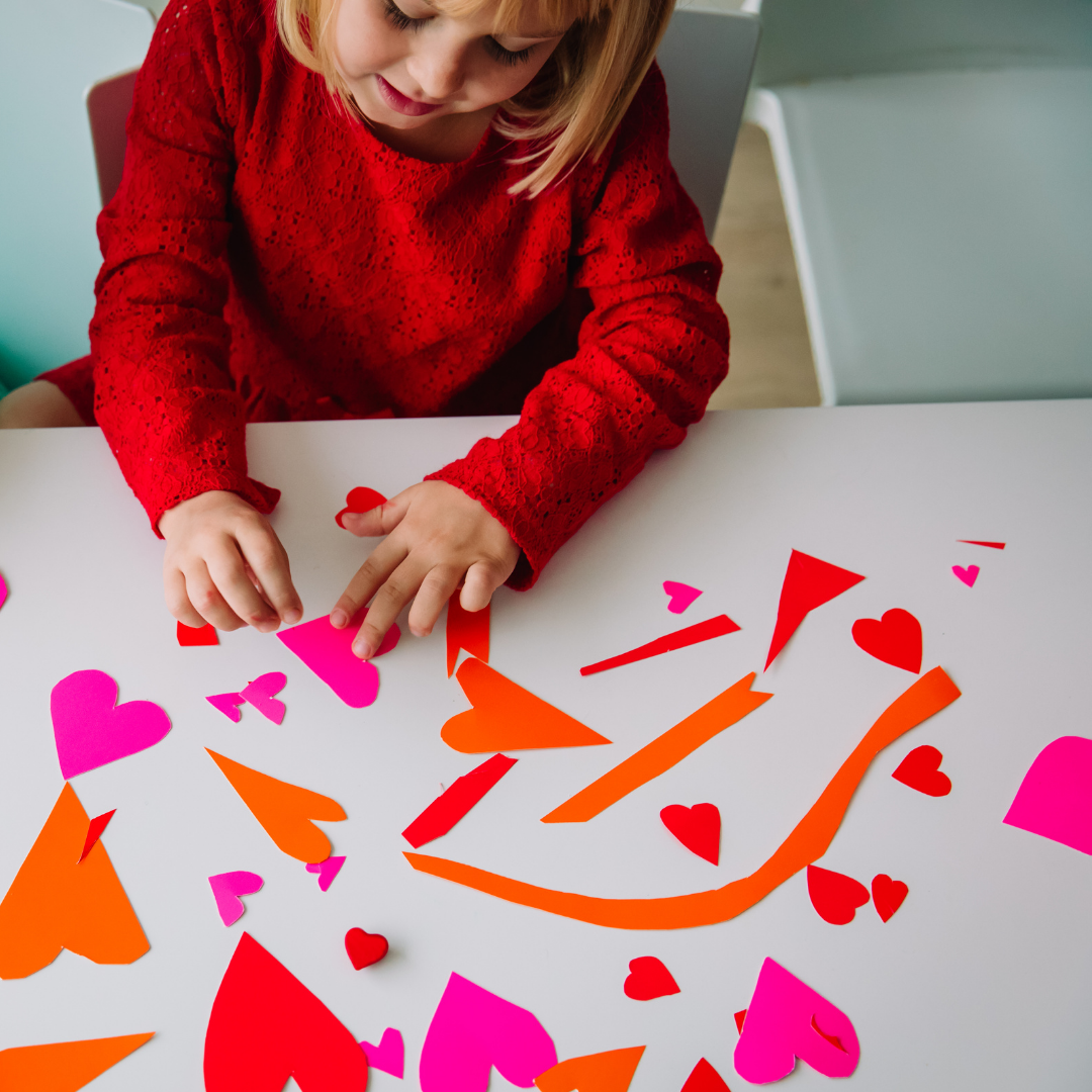 little girl playing with cutout hearts