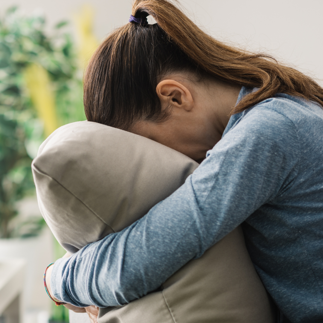 woman holding a pillow and crying