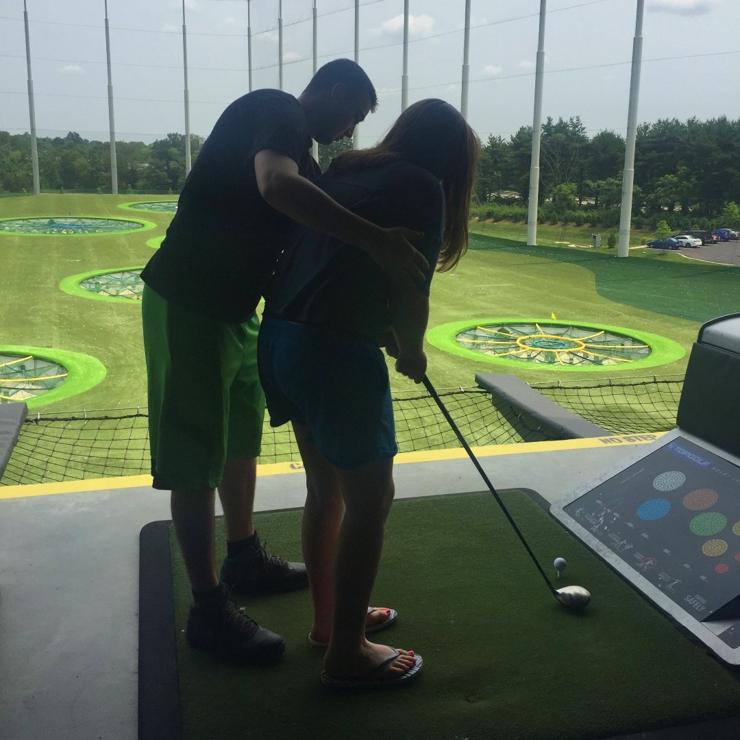 young man helping sister play golf