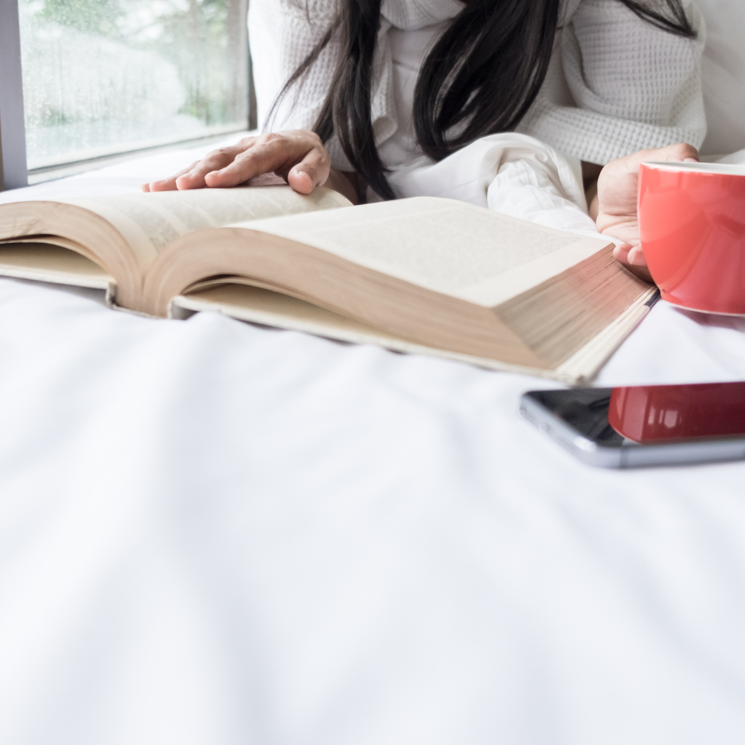 woman reading Bible with coffee and phone nearby