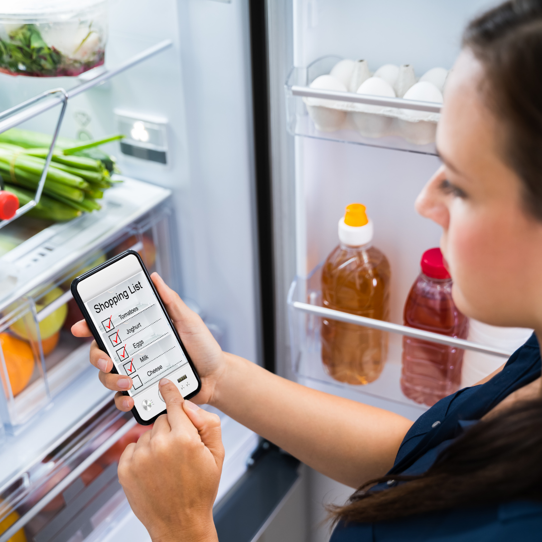 woman using app to make shopping list as she checks the fridge
