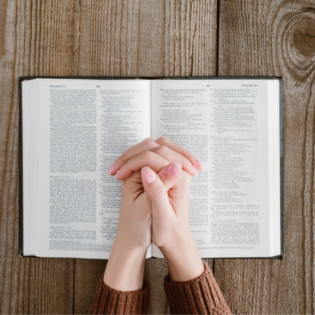 woman's hands folded on top of a Bible