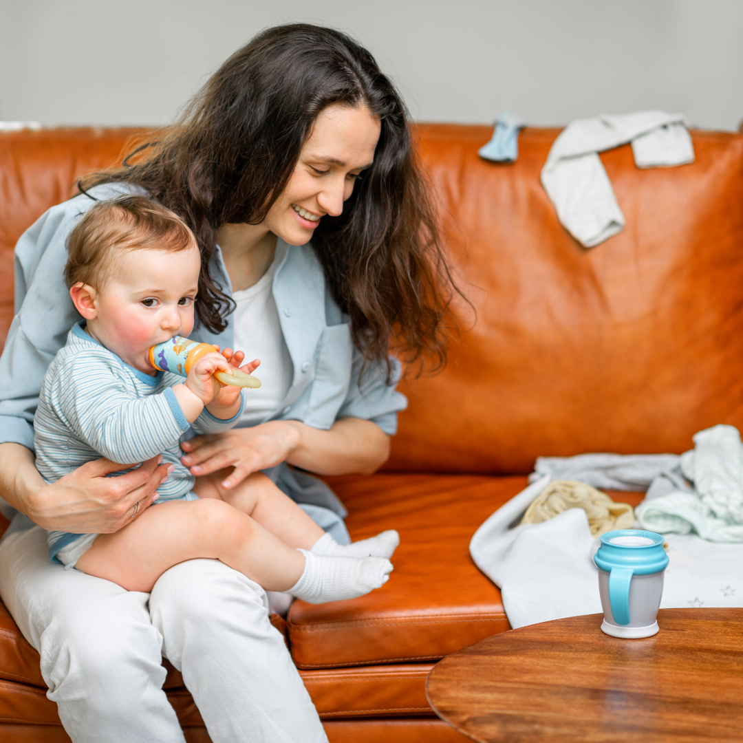 mom folding laundry and holding baby on the couch