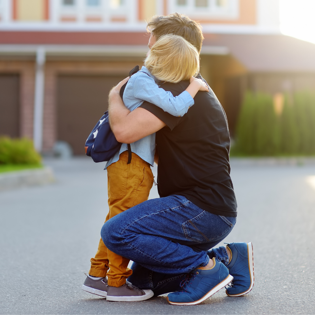 father hugging his little boy in the driveway