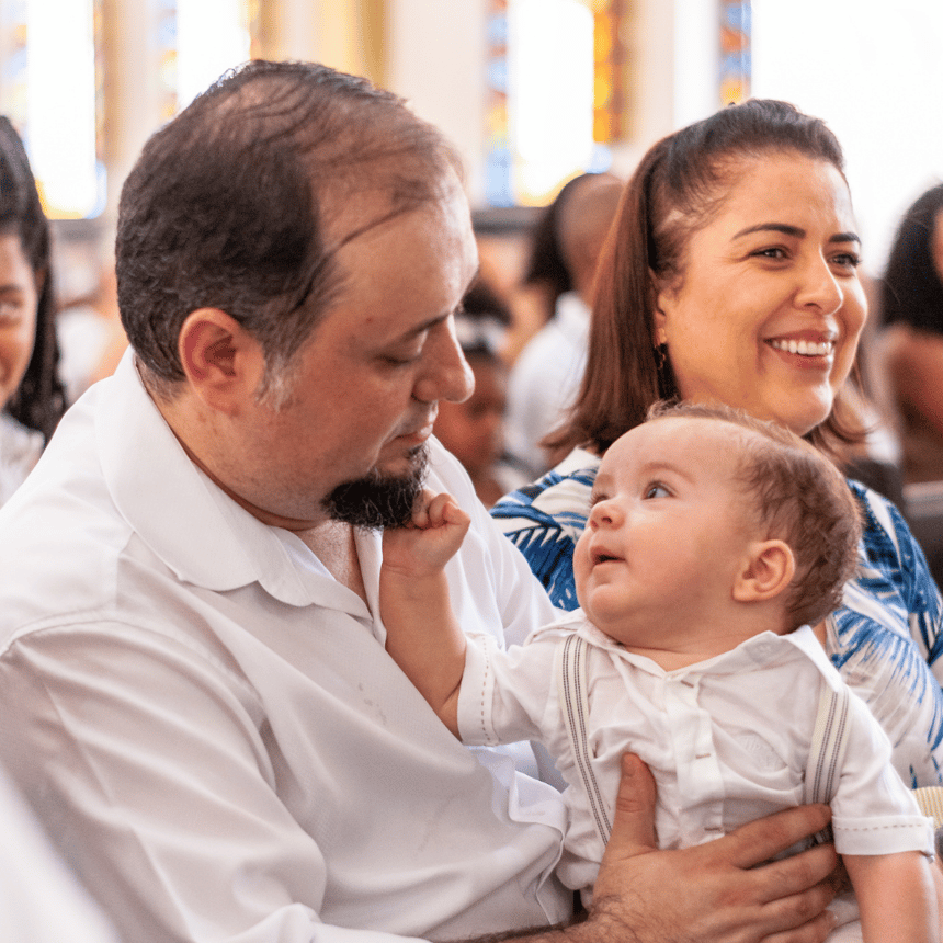 mom and dad sitting with baby in church pew