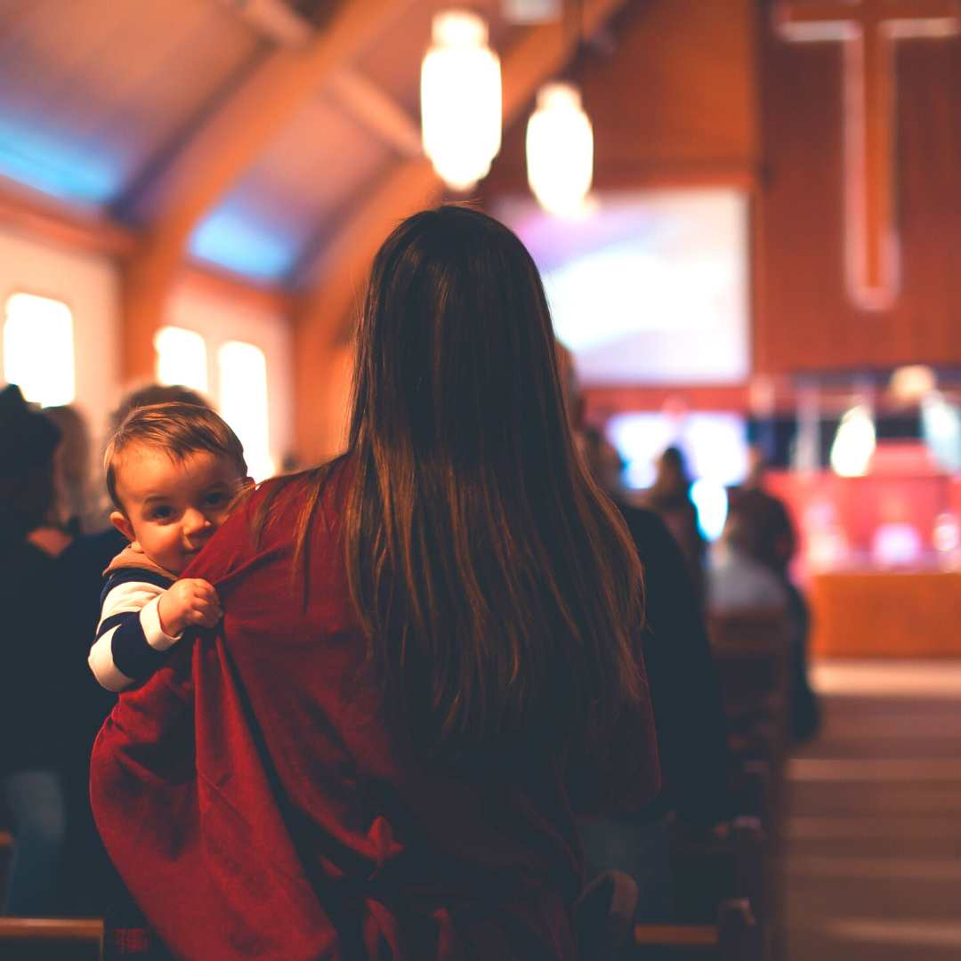 mom holding baby in back of church