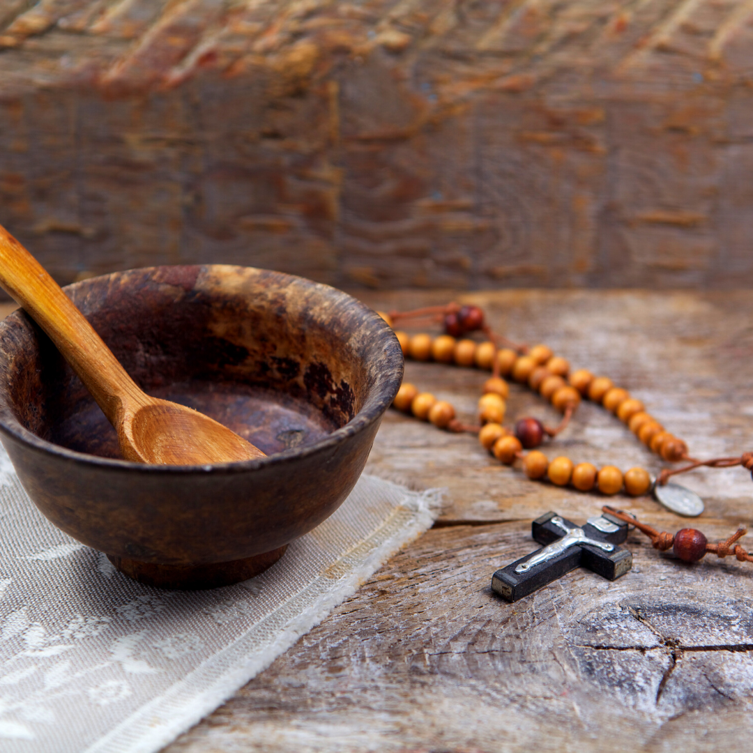 empty wooden bowl with spoon next to Rosary