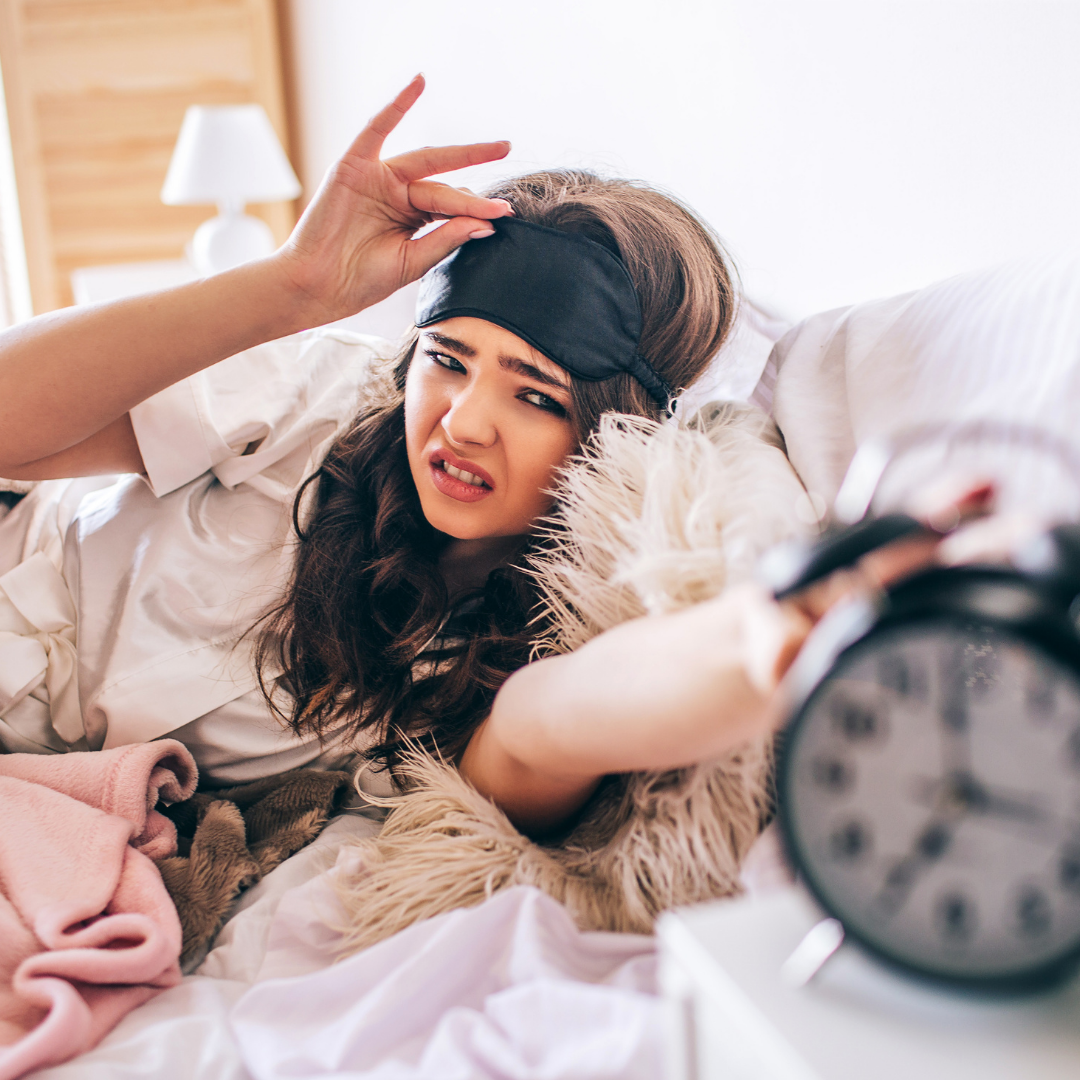 teenager peeking out from sleep mask and smacking alarm clock