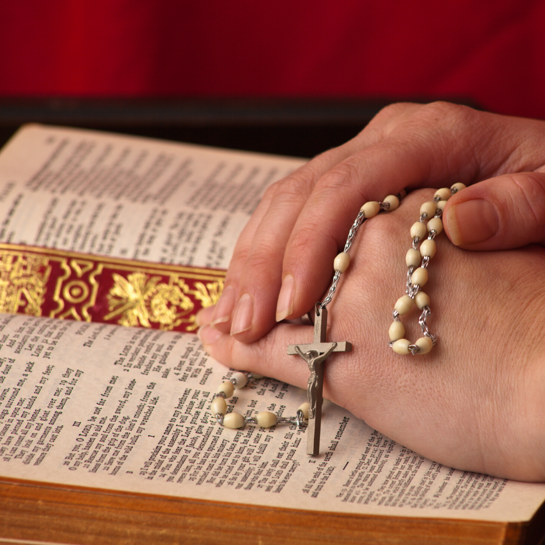 woman praying a Rosary with an open Bible
