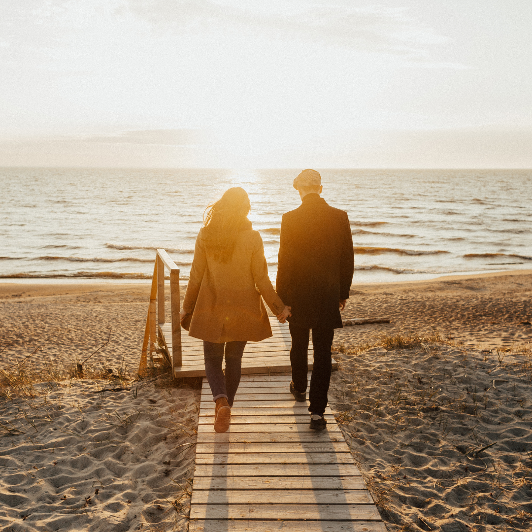 man and woman walking along path to beach