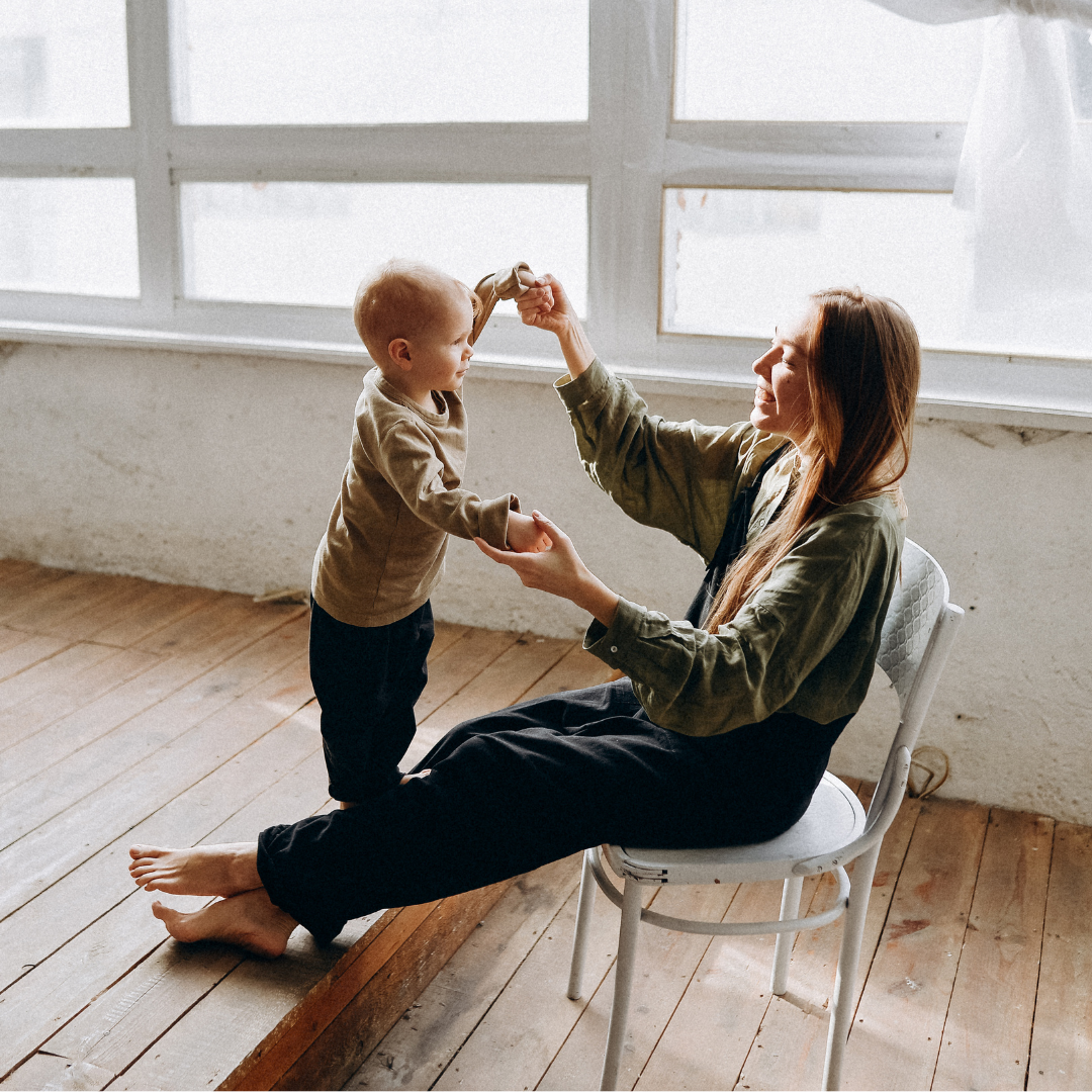 toddler balancing on mom's legs