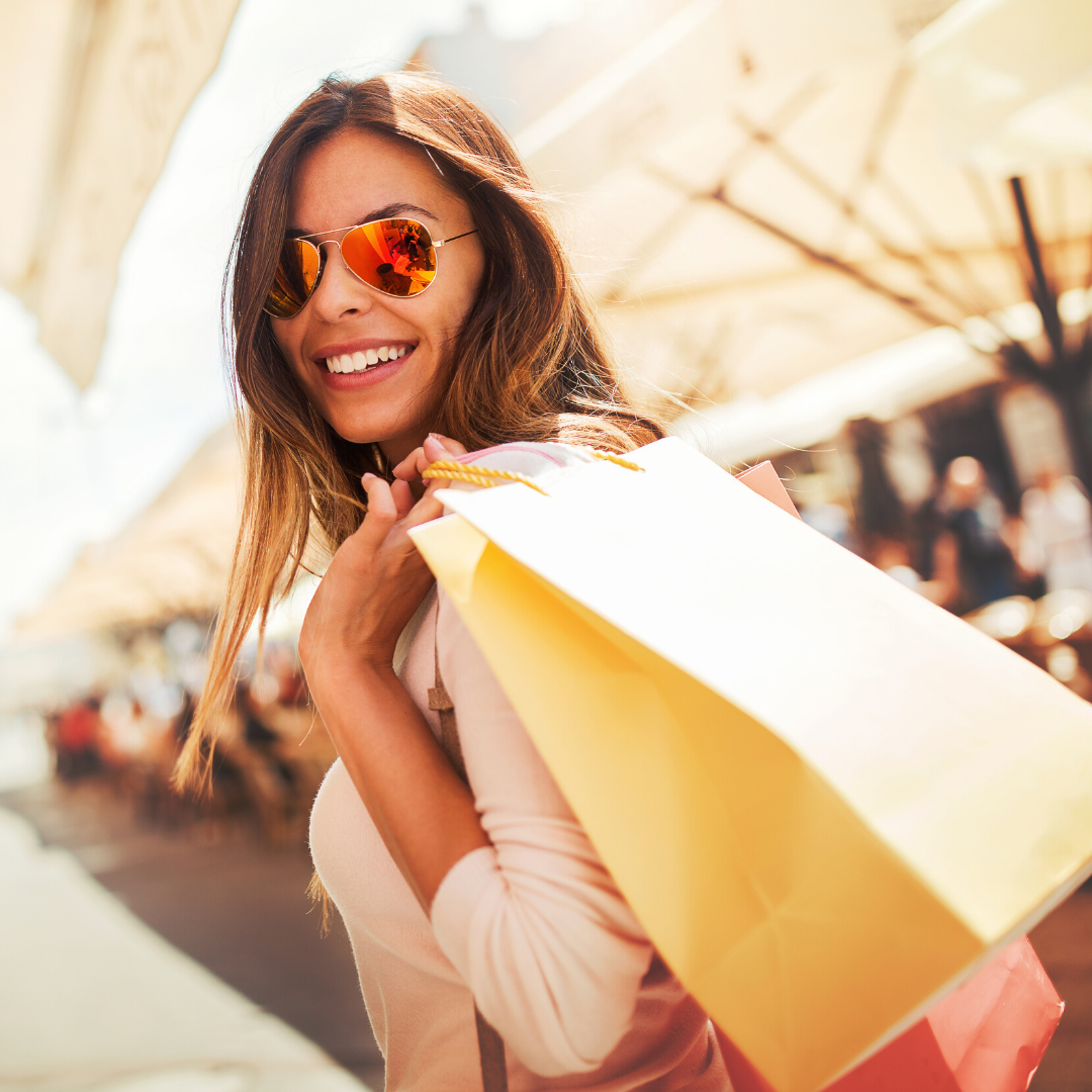 smiling woman in sunglasses holding shopping bags