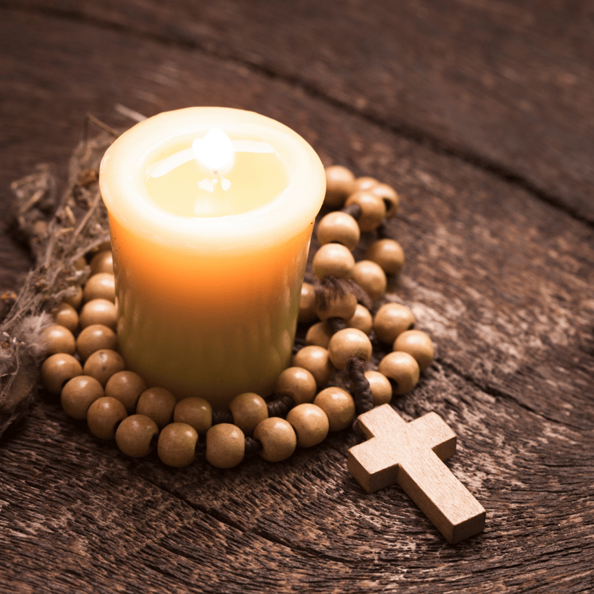 rosary and candle on table