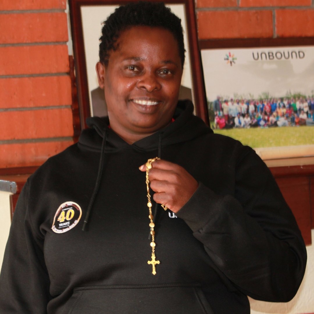 staff member Judita Ngumu holds her rosary while standing inside Unbound’s Nairobi program office