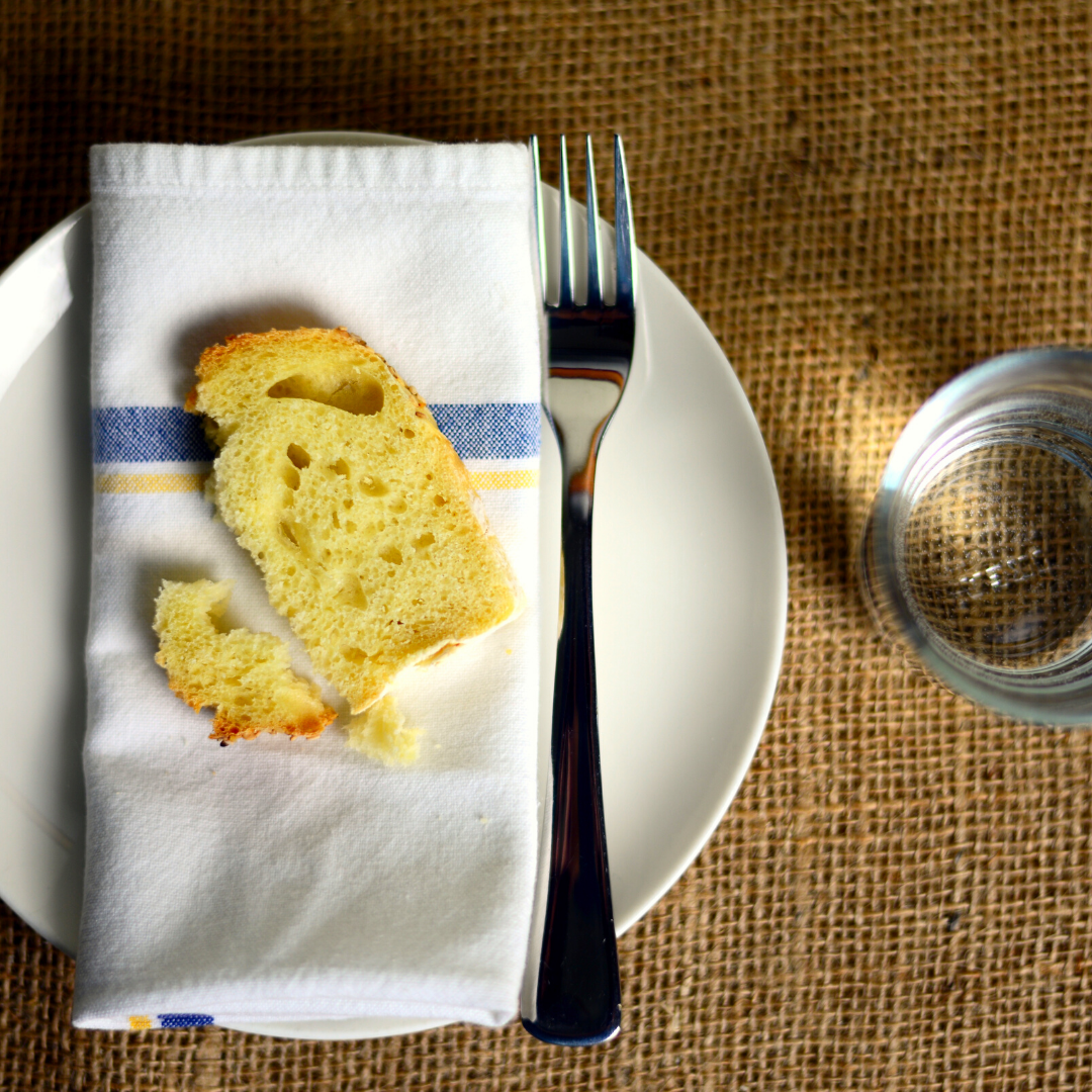 plate with cloth napkin, bread, and fork, and a glass of water