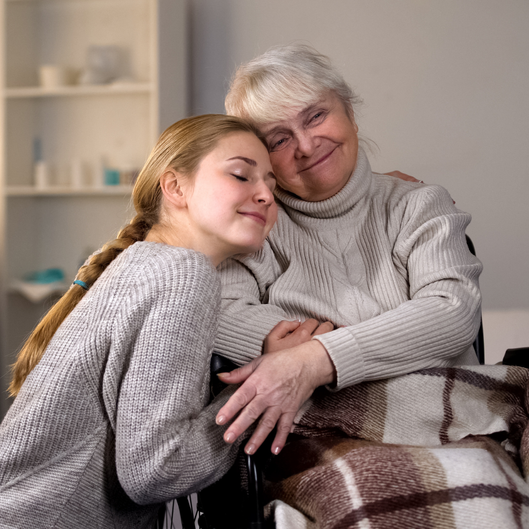young woman hugging older woman in wheelchair