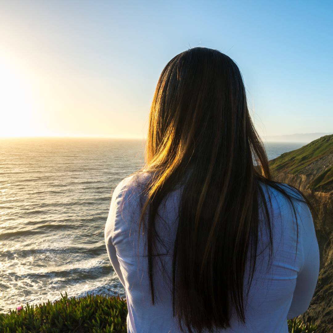 woman looking at sunrise over the ocean