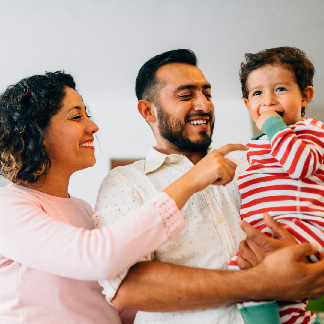 parents holding toddler and smiling at him