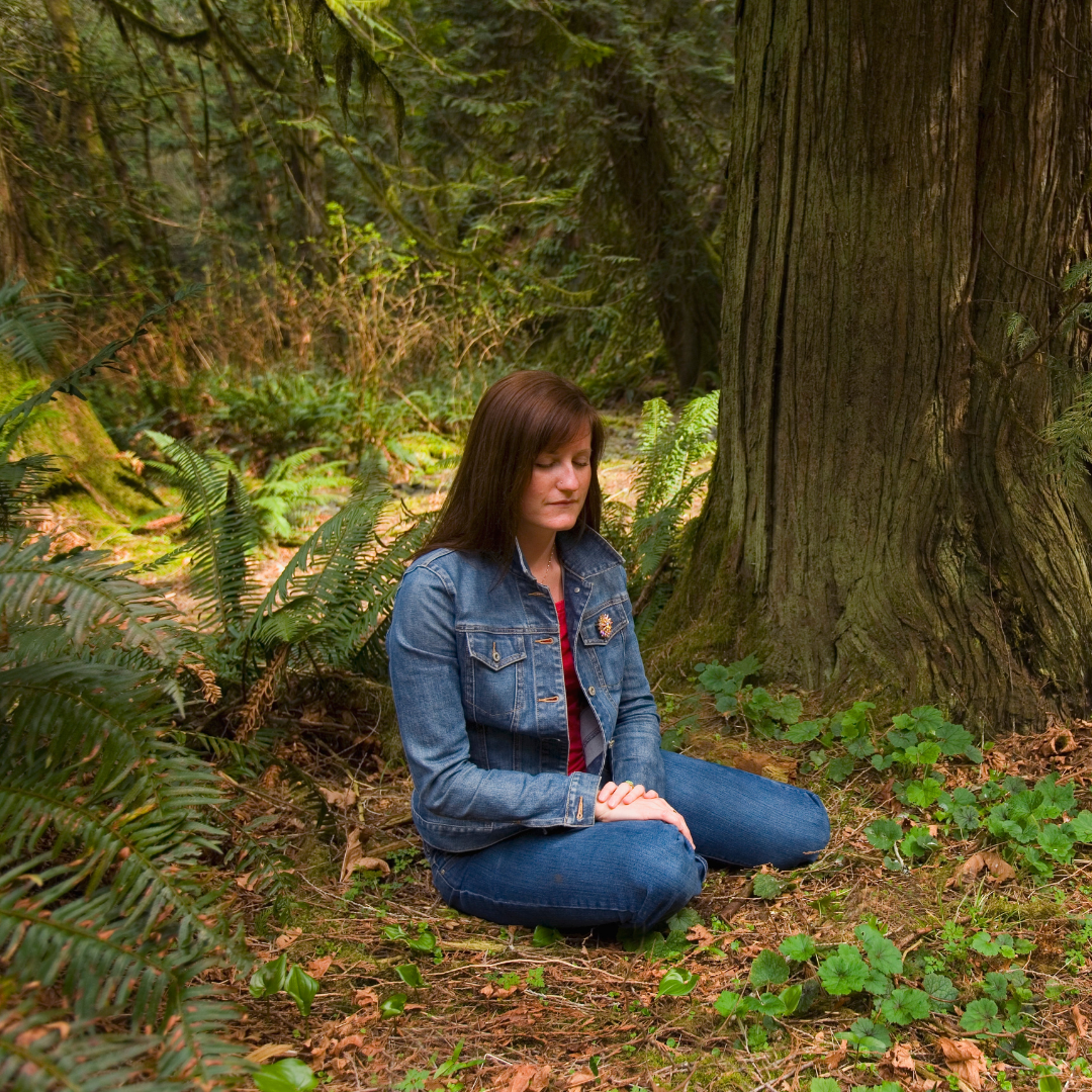 woman meditating under a large tree
