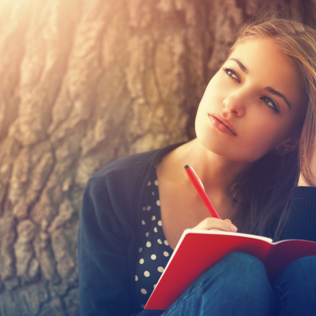 woman with journal under a tree