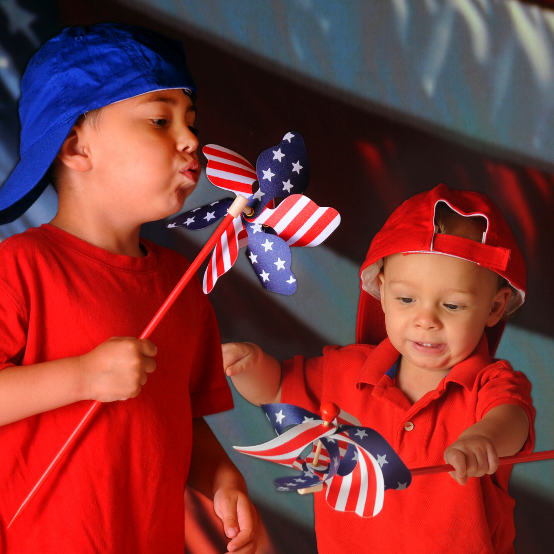 2 little boys playing with American flag pinwheels in front of American flag