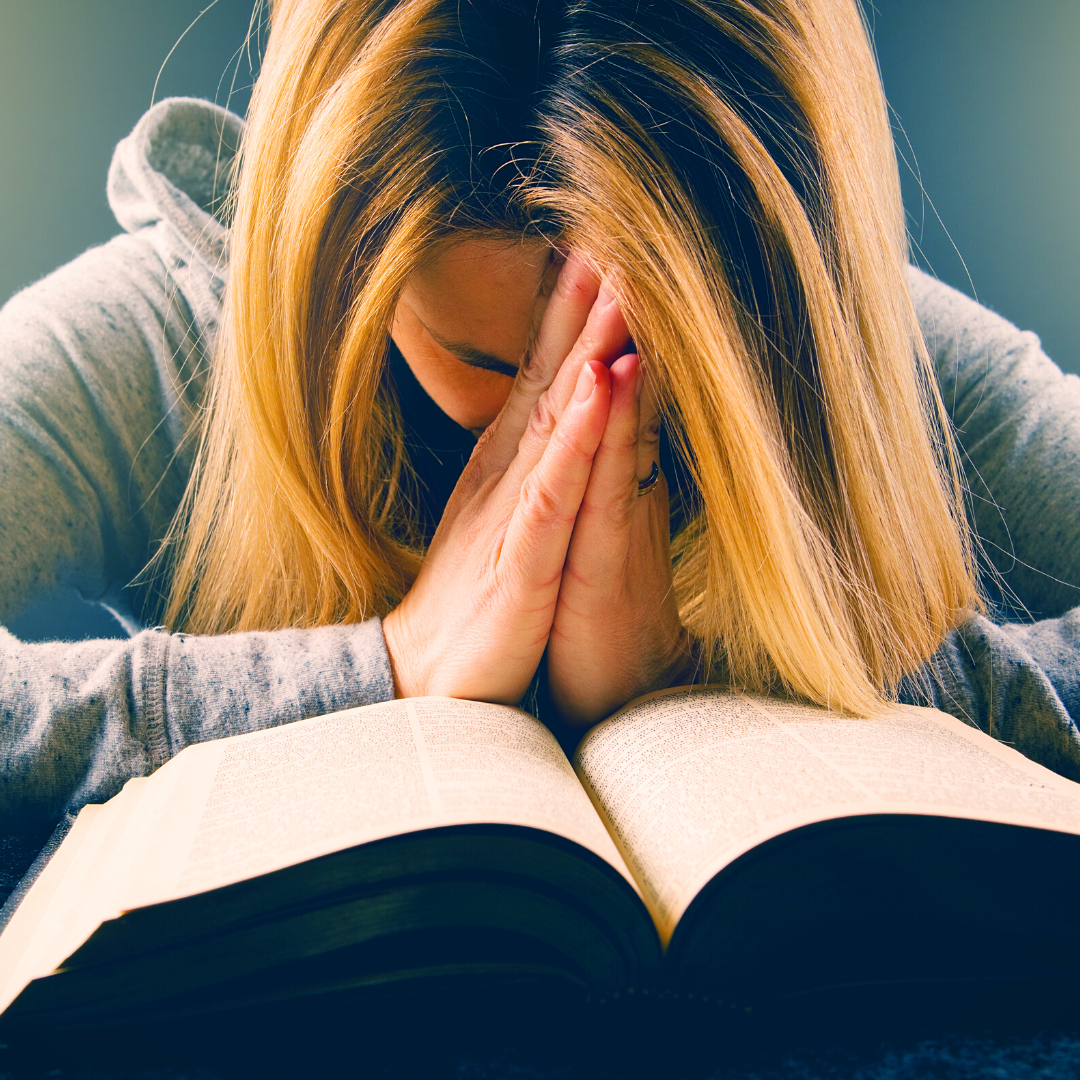 woman praying in front of Bible