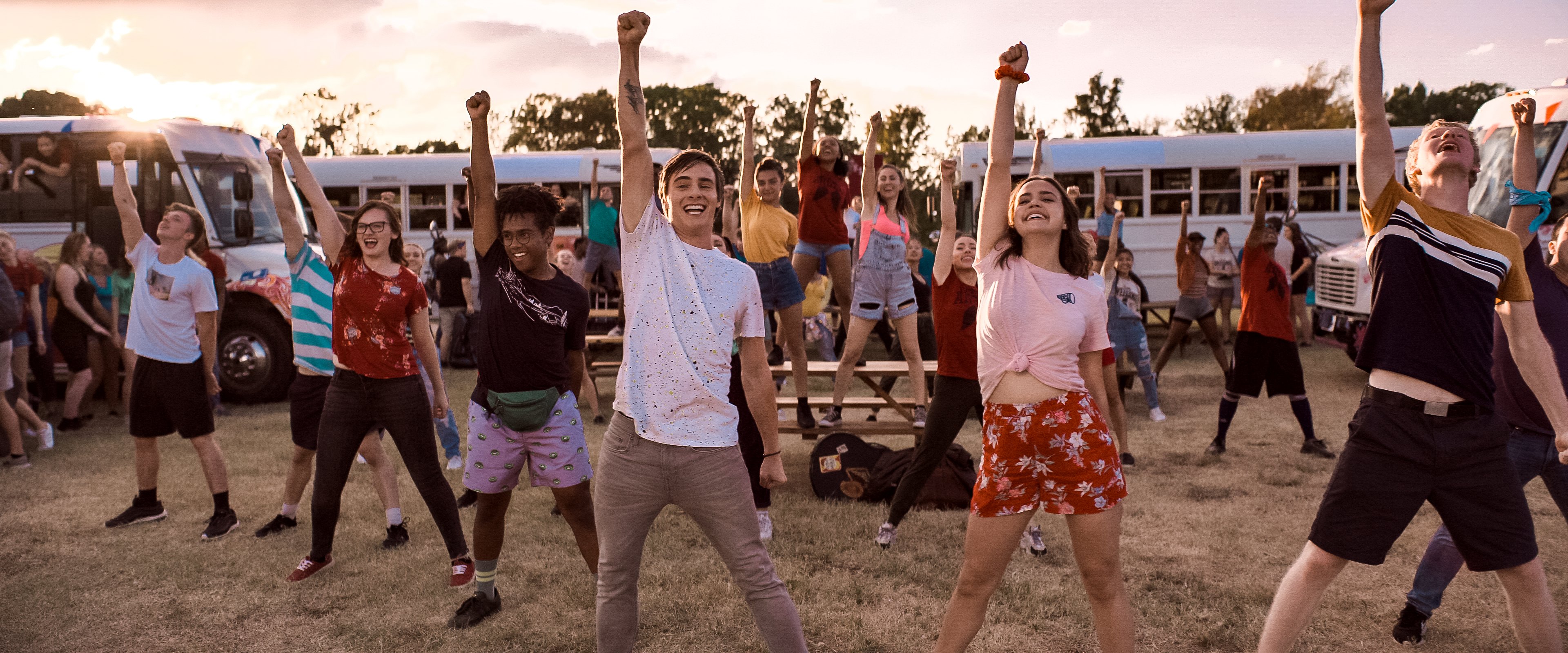 Teenagers dancing in front of camp buses