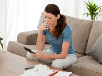 Anxious woman calculating her debts sitting in the living-room