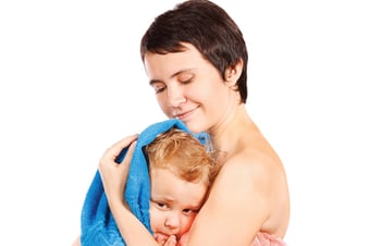 Mother wipes head to his son after bathing on a white background