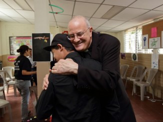 Bishop Gregory John Mansour of Brooklyn, New York, embraces Manuel,* a former gang member, during a recent visit to El Salvador. Photo by Silverlight for CRS.