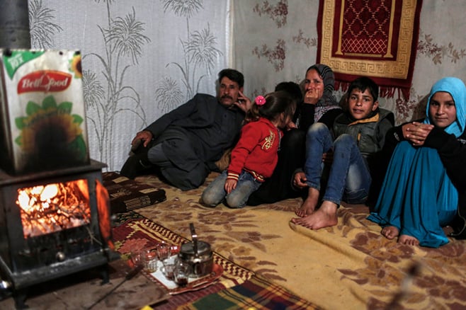 A CRS-supplied wood-burning stove helps warm a family's tent. "Without the heater and the wood we would have died from the cold," says Sabah, the children's mother. "It was difficult finding wood in a snowstorm," she says. Photo by Sam Tarling for CRS