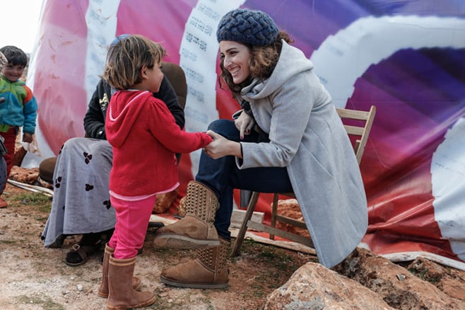 Soha Menassa, a CRS project manager in Lebanon, talks with a Syrian child from Raqqa at the Bachir informal tent settlement in Deir al Ahmar in Lebanon's Bekaa Valley. Photo by Sam Tarling for CRS