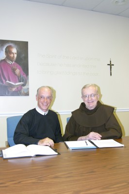 Fr. Don Willard, CSsR, president, Liguori Publications, signs a collaborative agreement with Fr. Dan Kroger, OFM, publisher/CEO, Franciscan Media.