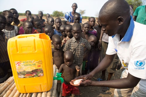 Samuel Nyariel, a CRS volunteer hygiene promoter, gives a hand-washing demonstration to children at a displacement camp. Hand-washing helps stop the spread of disease in crowded conditions.